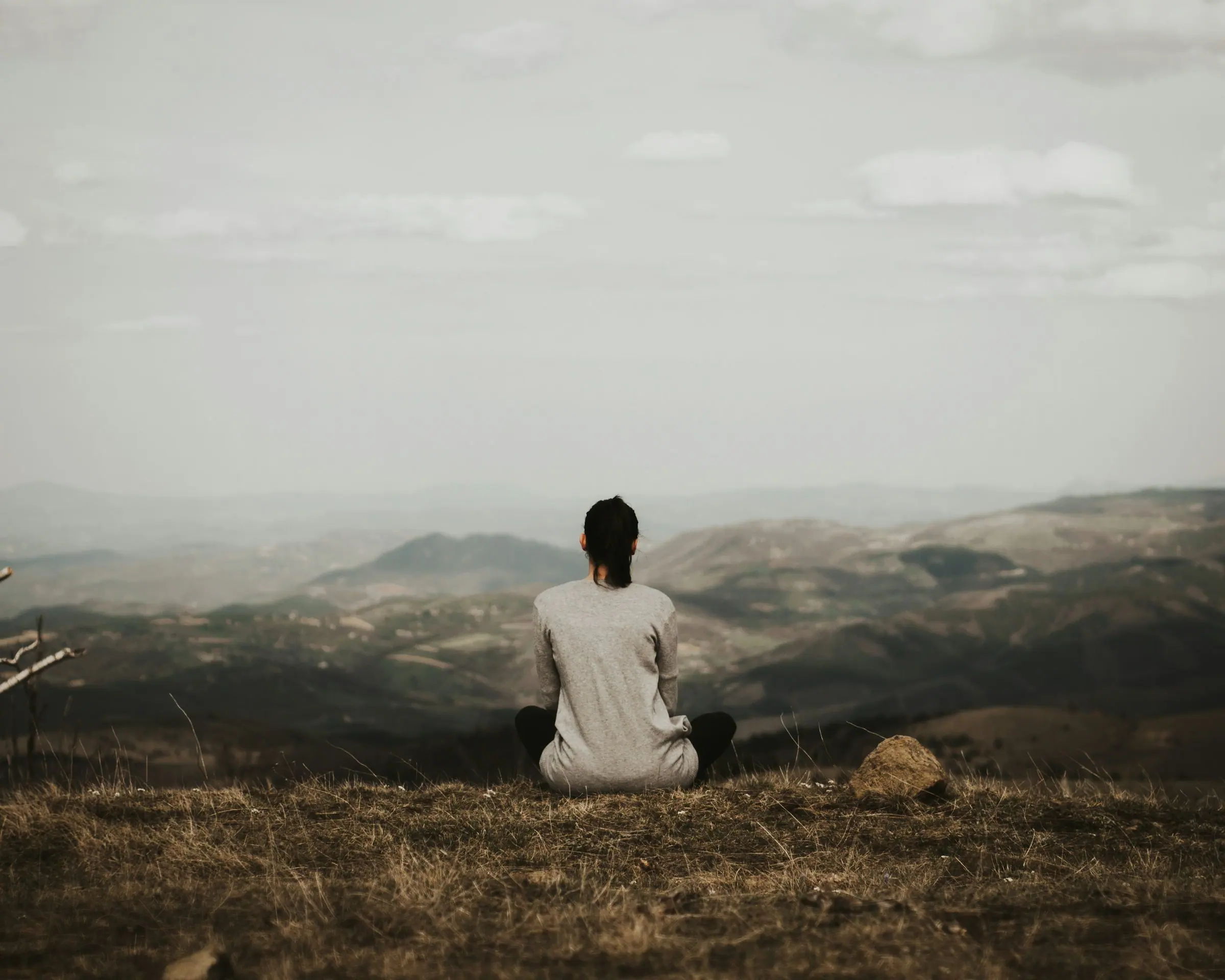 A guest sitting in meditation on a ridge above a forested valley